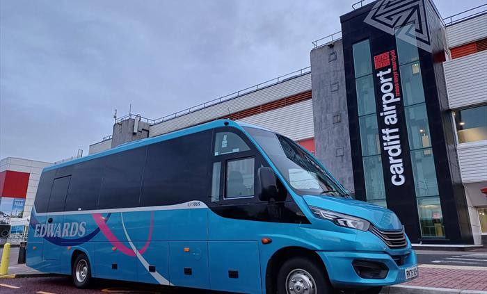 A blue mini bus parked outside an airport